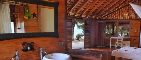 Un baño de madera con dos lavamanos, un espejo y vista a la playa.