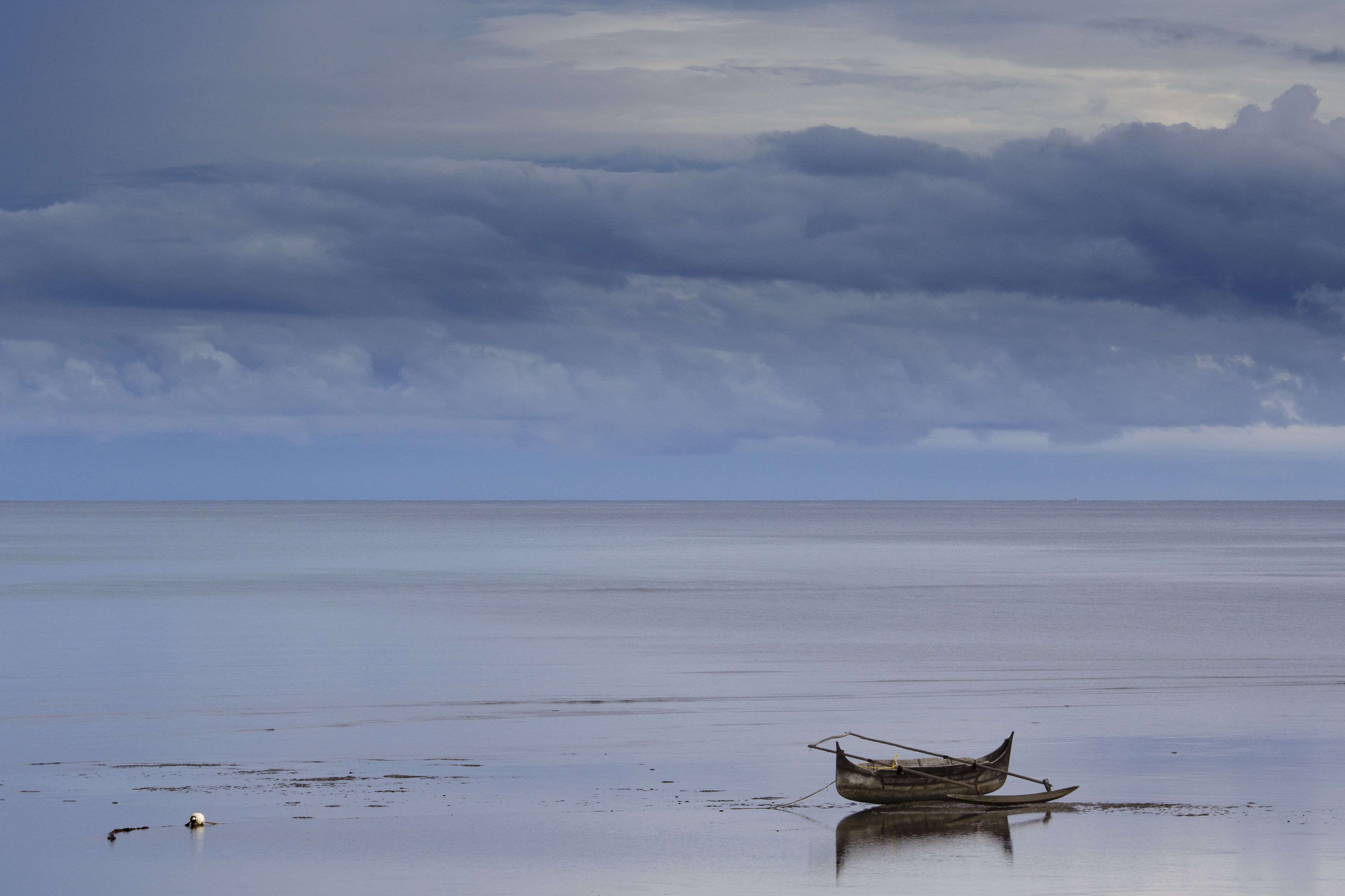 A calm sea with a small boat on the shore.