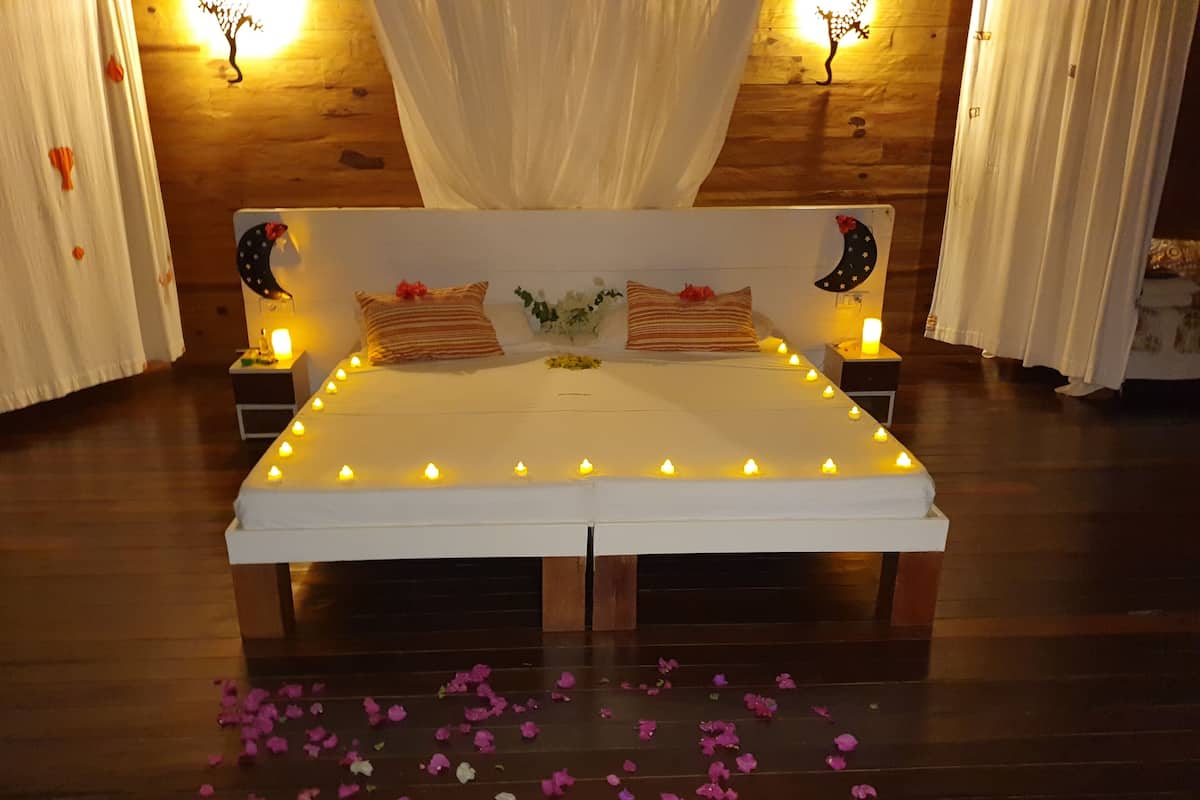 Una cama con ropa de cama blanca, varios almohadones y dosel.
