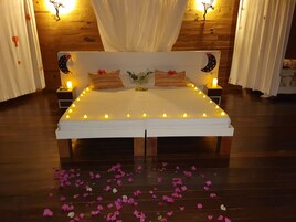 Una cama con ropa de cama blanca, varios almohadones y dosel.