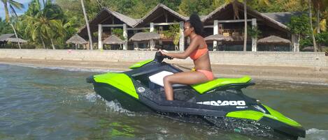 A person riding a green and black Sea-DOO jet ski on calm water.