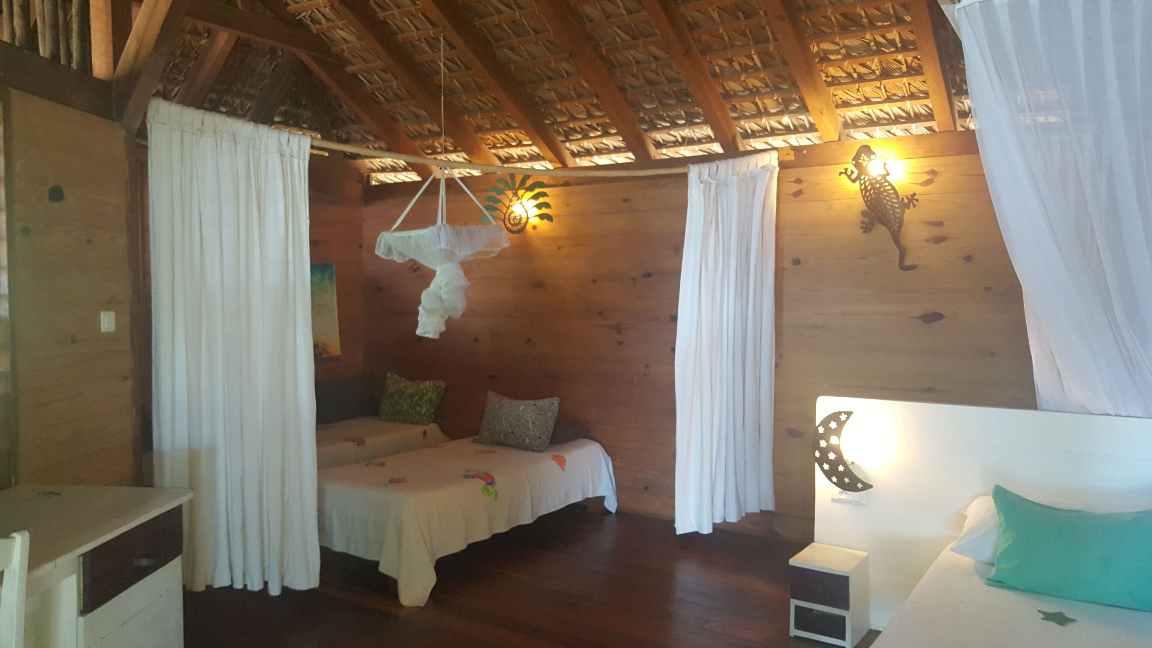 A cozy room with a wooden ceiling, a bed with a canopy, a small table, and a nightstand.