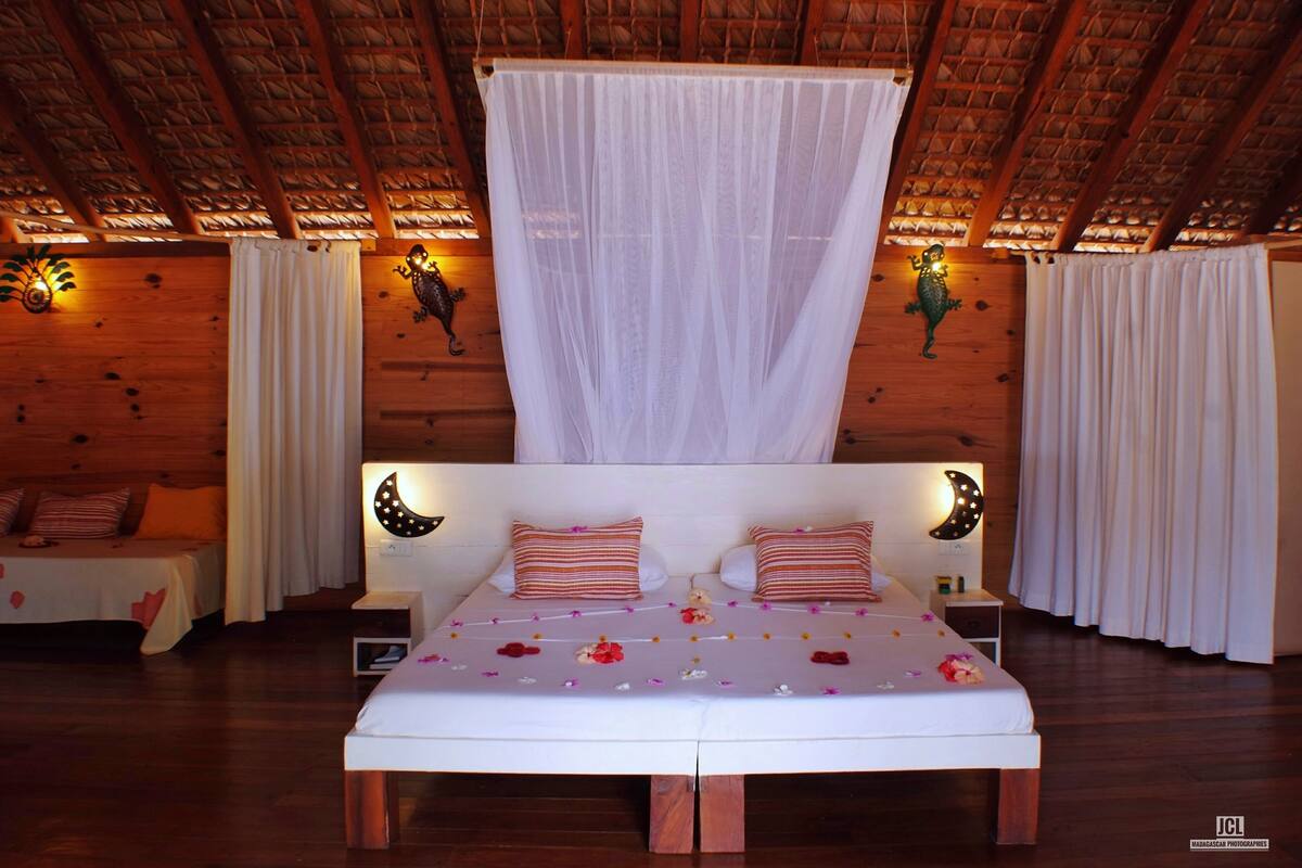 Una habitación de madera con una cama, dos mesitas de noche y un dosel.