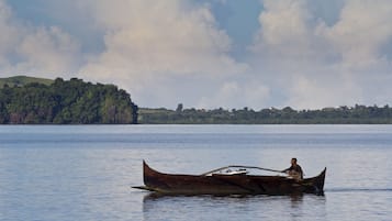 Un bote de madera tradicional navegando en aguas tranquilas, con una persona remando.