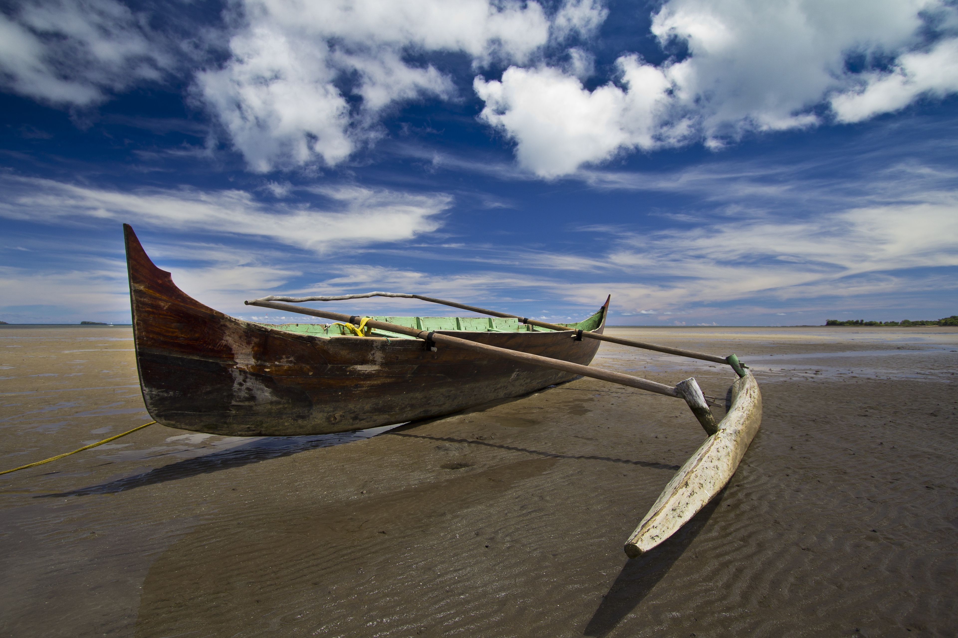 A wooden boat on a sandy beach with a clear sky.
