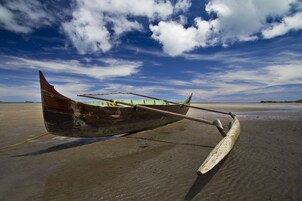 Un bote de madera en una playa arenosa bajo un cielo despejado.