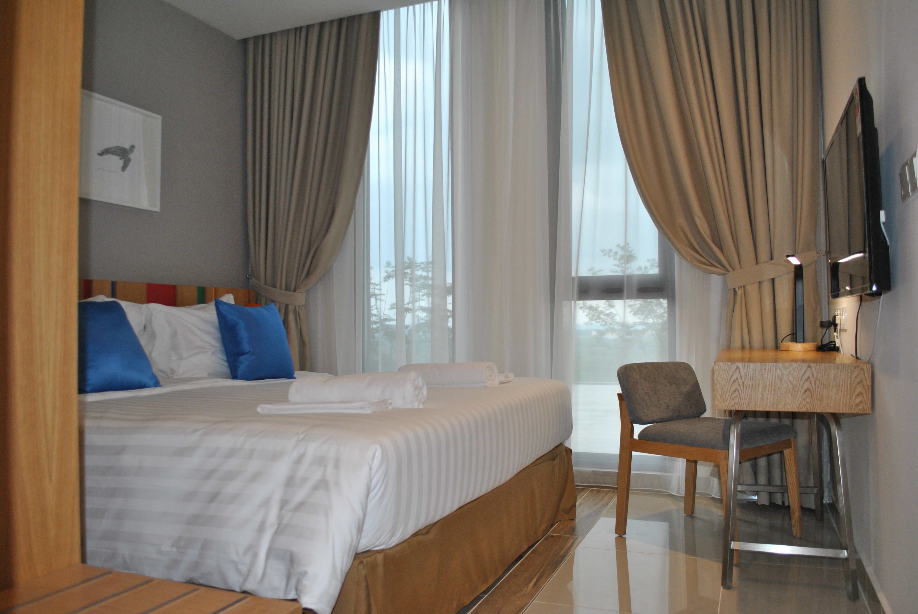 Una habitación de hotel con una cama grande, un escritorio con una silla y un televisor.