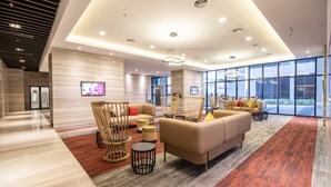 A spacious lobby with a modern design, featuring a large sofa, chairs, and a flat-screen TV mounted on the wall. - Ramada by Wyndham Meridin Johor Bahru (Iskandar Puteri)
