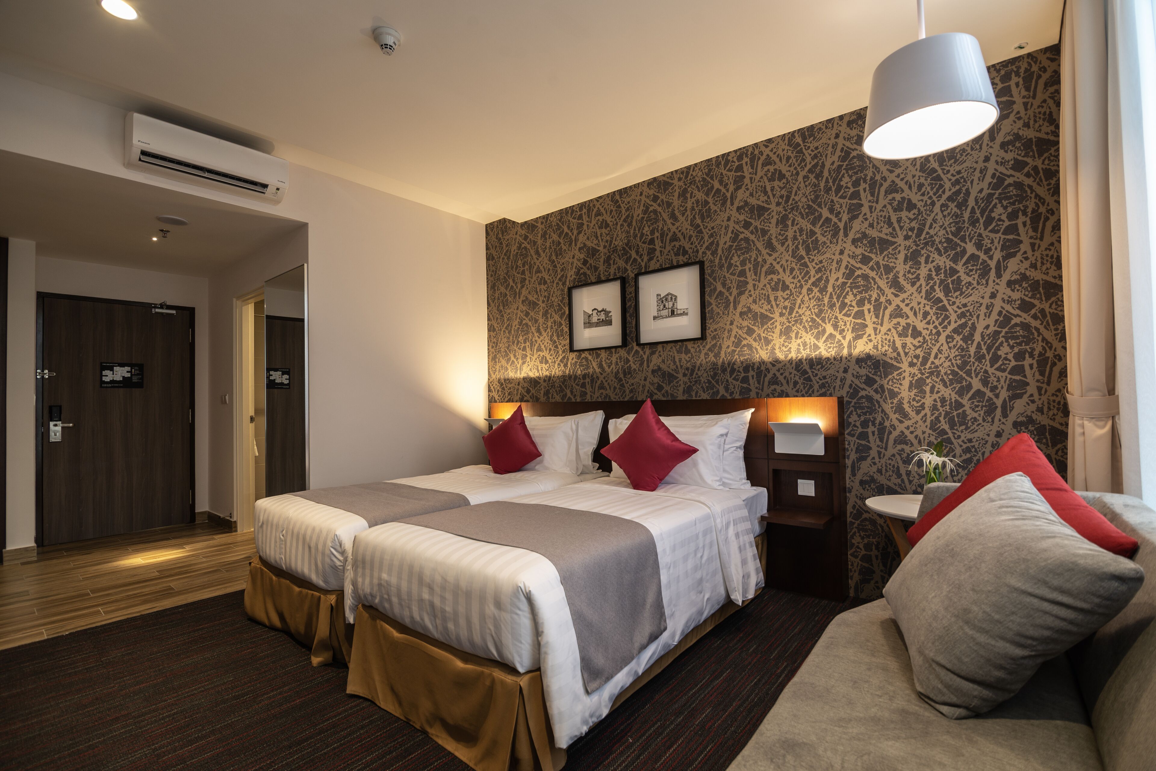 Una habitación de hotel con dos camas, una mesita de noche, una pequeña mesa y un sofá.