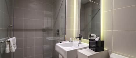 Ein modernes Badezimmer mit einer gläsernen Duschkabine, zwei Waschbecken und einer Toilette.