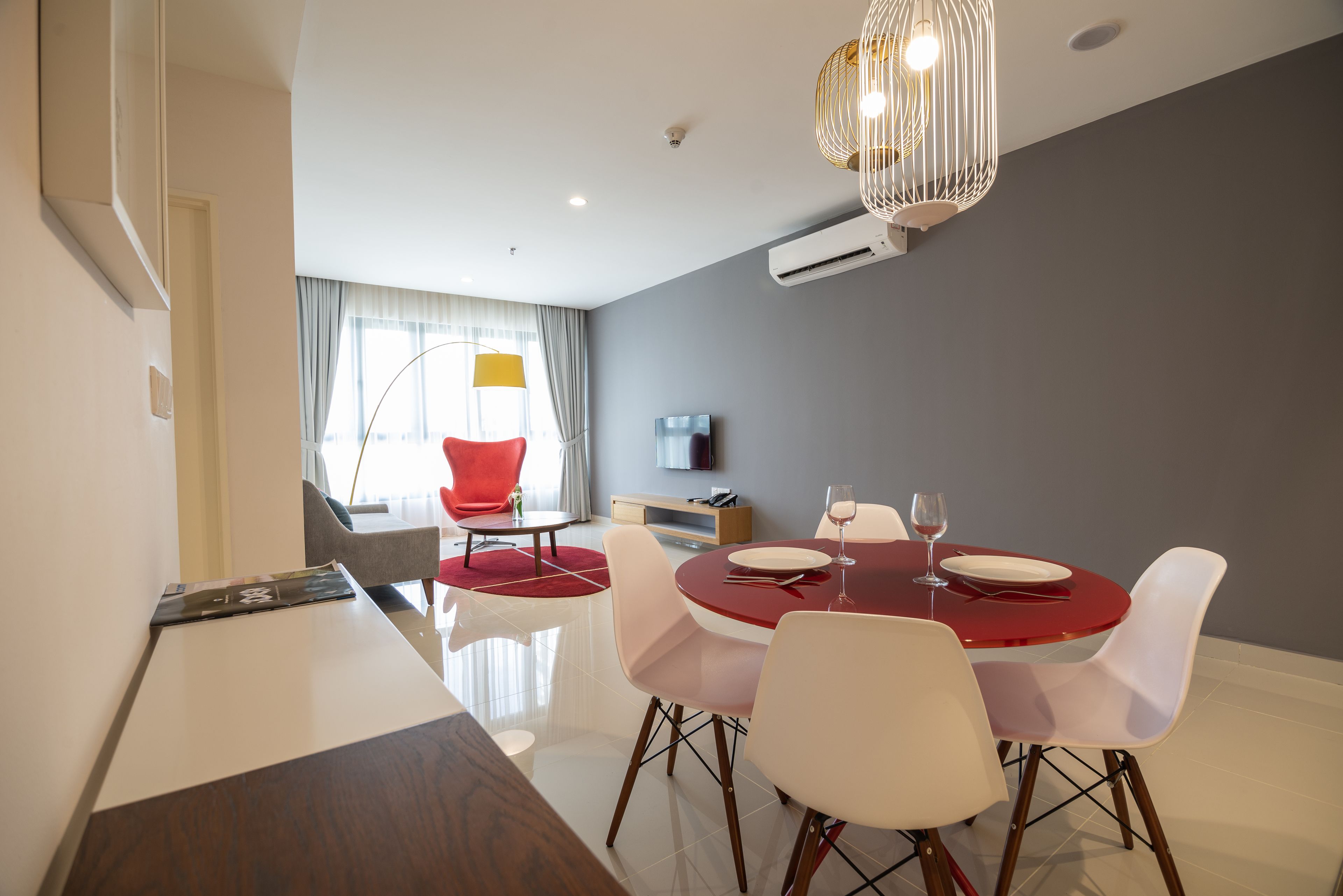 Uma sala de jantar moderna com uma mesa redonda, cadeiras brancas e toalha de mesa vermelha.