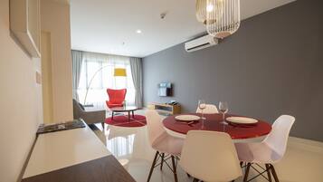 Uma sala de jantar moderna com uma mesa redonda, cadeiras brancas e toalha de mesa vermelha.