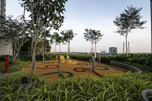 A playground with exercise equipment, surrounded by trees and greenery.
