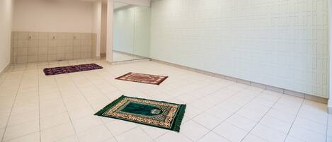 A spacious room with a tiled floor, a large mirror, and a patterned carpet.