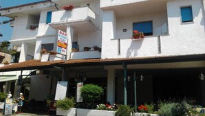 A multi-story building with a white facade, balconies with flower boxes, and a signboard indicating a bar and restaurant. - Pensione Nettuno (Centola)