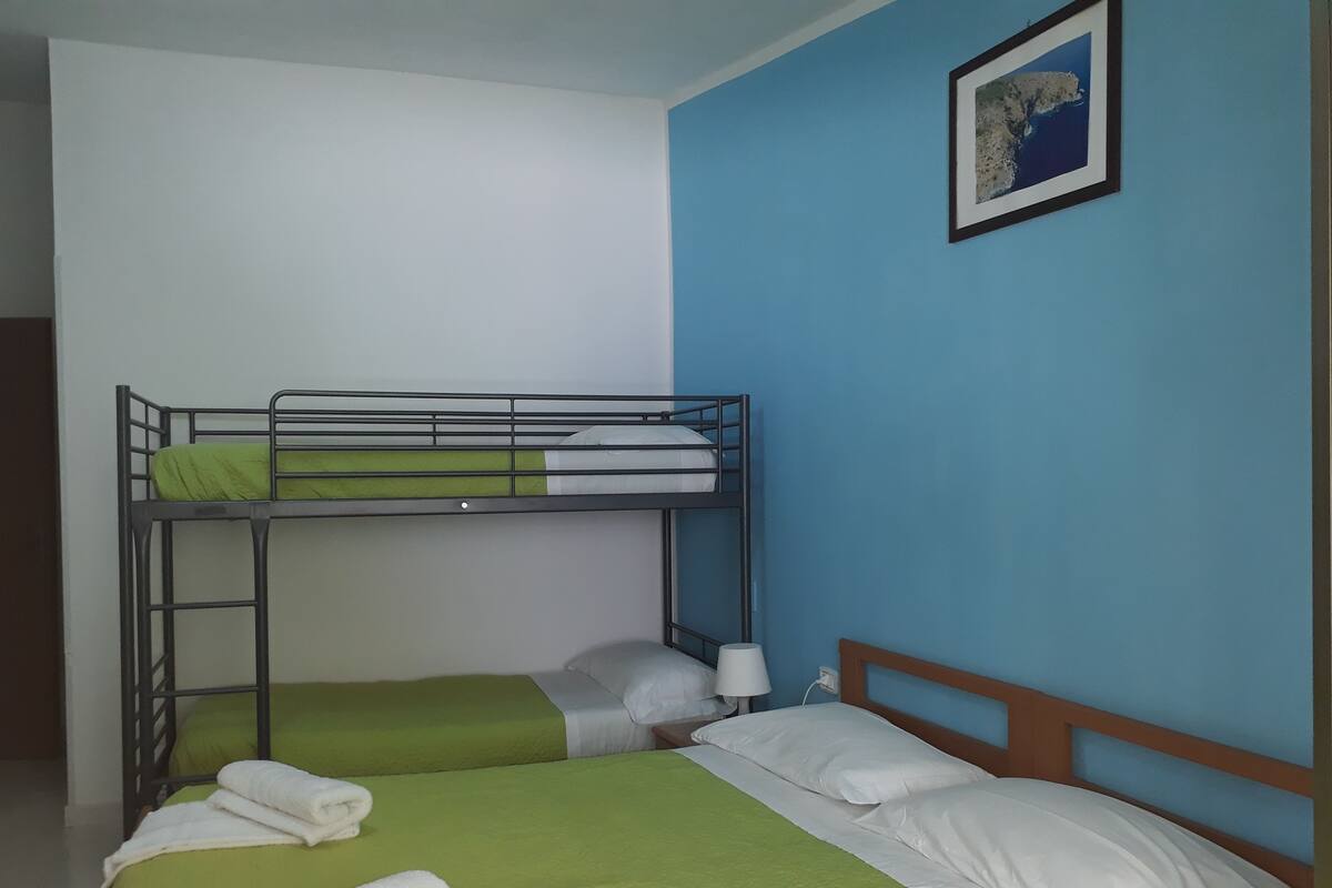 A bunk bed room with green bedding, a white pillow, and a framed picture on the wall.