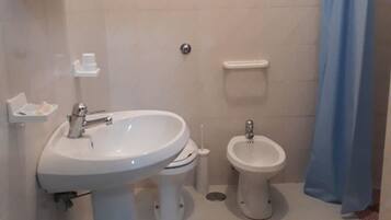 Ein Badezimmer mit Waschbecken, Toilette, Bidet und Duschvorhang.