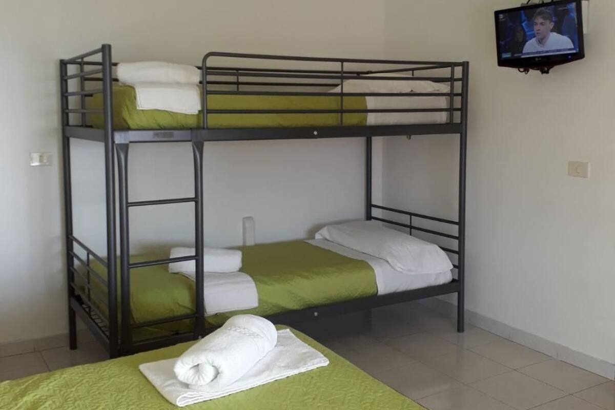 A bunk bed room with a television on the wall.