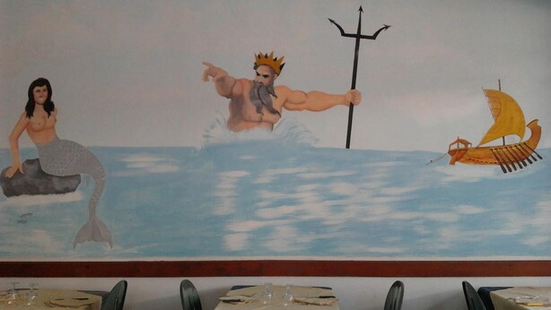 A mural of a mermaid, a muscular man with a trident, and a sailboat on a calm sea. - Pensione Nettuno (Centola)