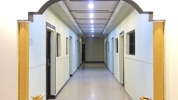 A long, narrow hallway with doors on both sides, a ceiling with recessed lighting, and a polished floor. - Hotel Mangalam Palace - Lucknow Airport (Lucknow)