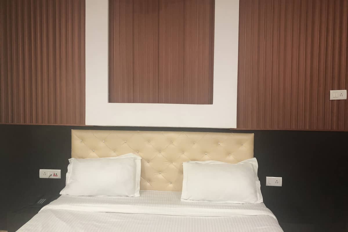 A hotel room with a tufted headboard, two white pillows, and a bed with white bedding.