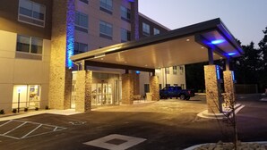 A hotel entrance with a covered parking area, stone pillars, and a blue-lit facade.