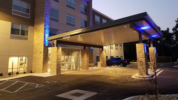 A hotel entrance with a covered parking area, stone pillars, and a blue-lit facade.