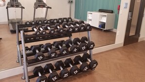 A gym with treadmills, a mirror, and a rack of dumbbells.