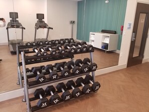 A gym with treadmills, a mirror, and a rack of dumbbells.