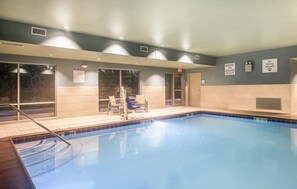 An indoor swimming pool with clear pool rules and no diving allowed signs.