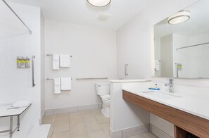A modern bathroom with a white sink, mirror, and toilet.
