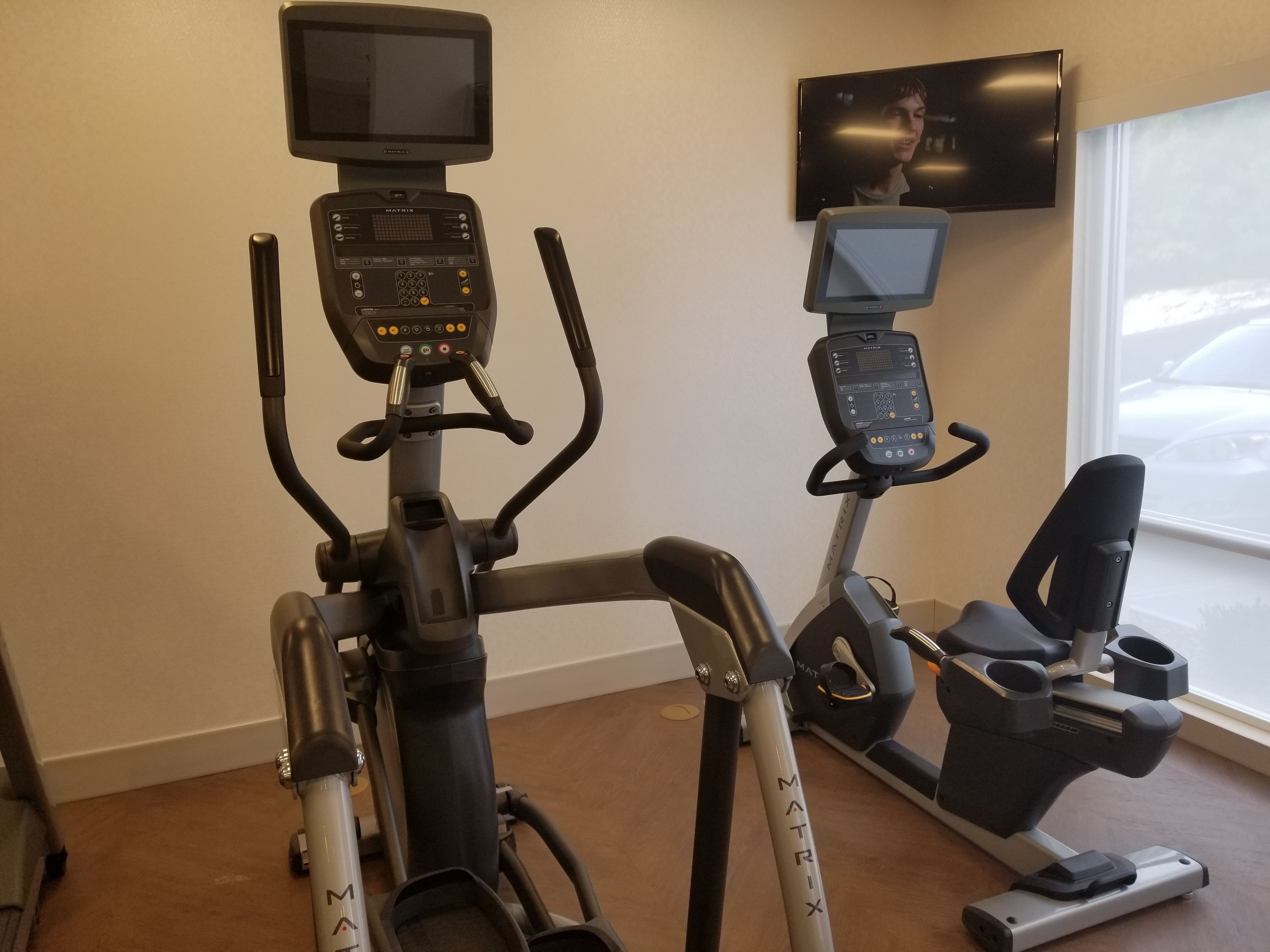 Una bicicleta estática con pantalla digital y un televisor colgado en la pared.