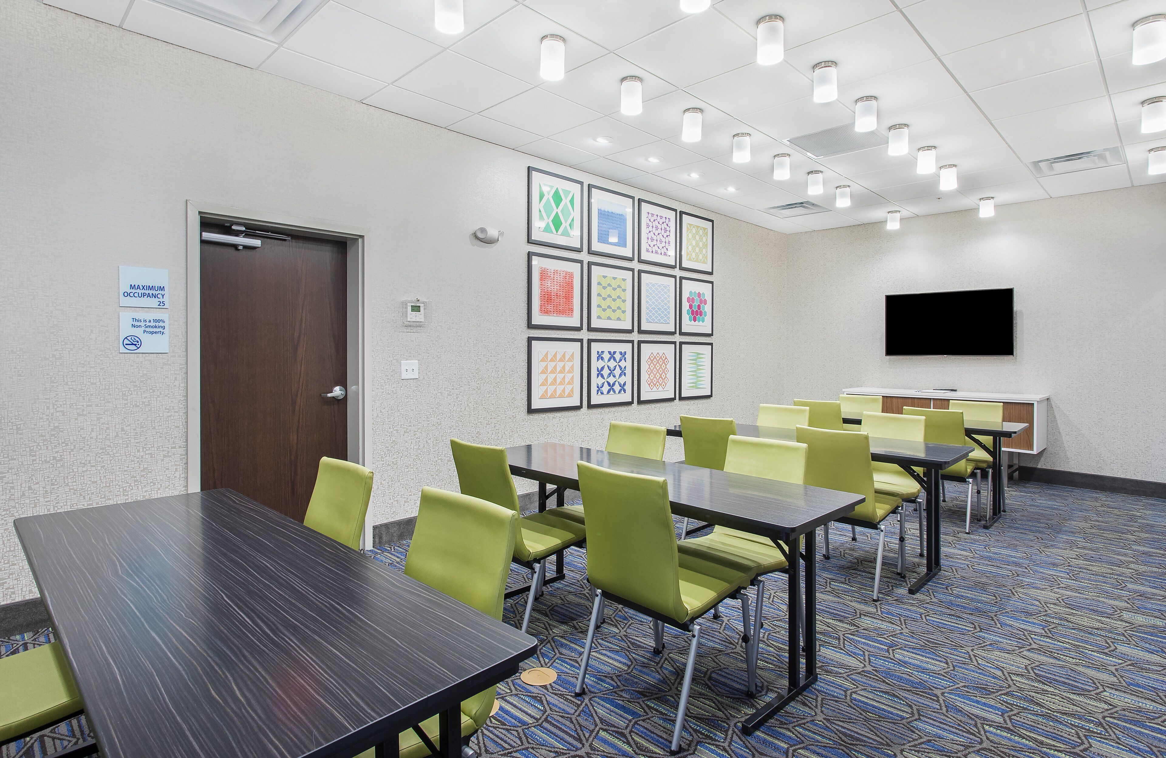 A conference room with tables and chairs, a television, and framed artwork on the wall.