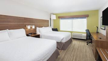 Ein Hotelzimmer mit zwei Betten, einem Schreibtisch, einem Stuhl, einem Fernseher und einem Fenster mit Jalousien.