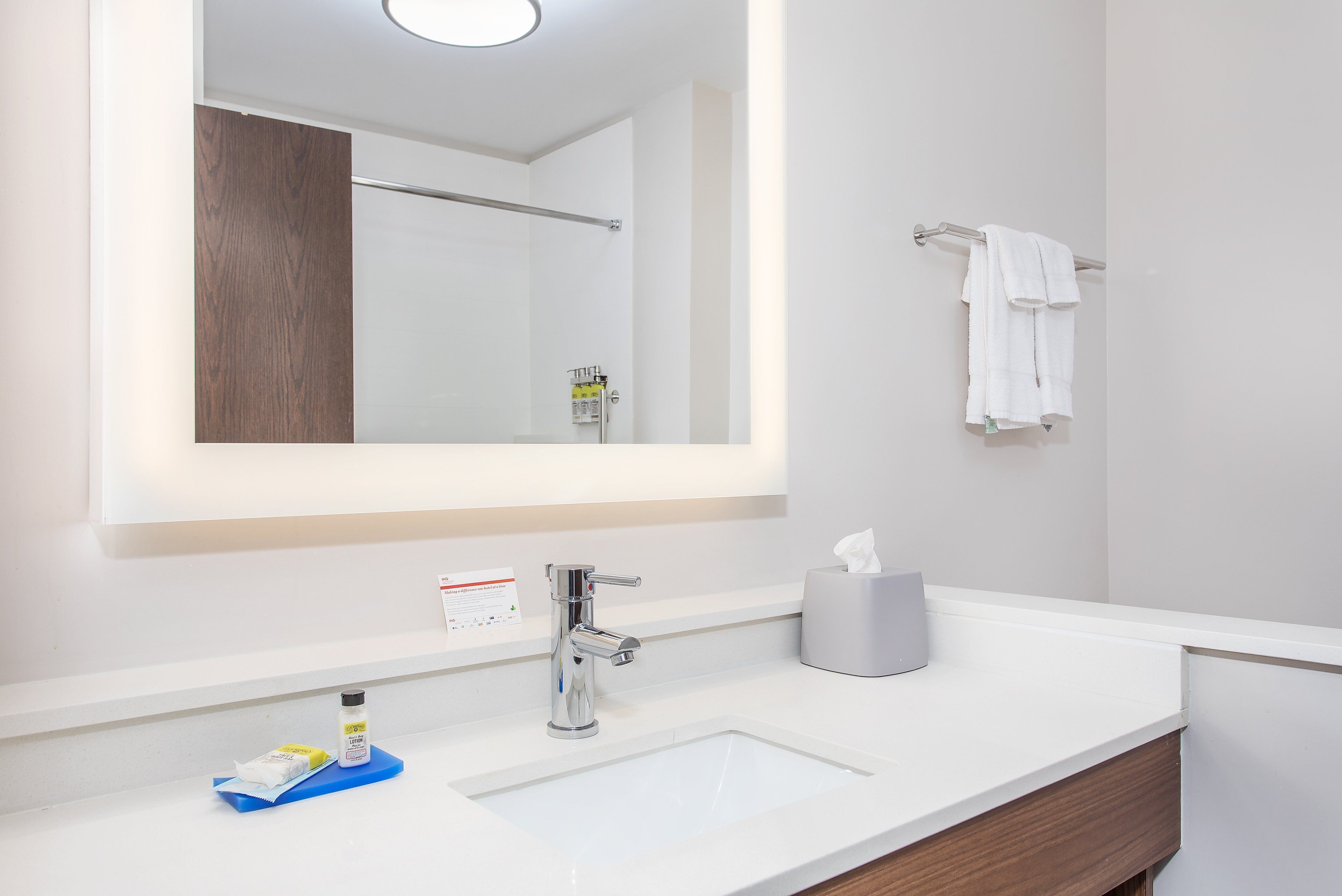A bathroom with a white sink, a mirror, a towel rack, and a tissue dispenser.