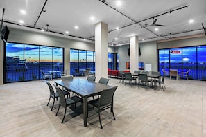 A spacious conference room with a large table and chairs, large windows with a city view, and ceiling fans. - Holiday Inn Lubbock South by IHG (Lubbock)
