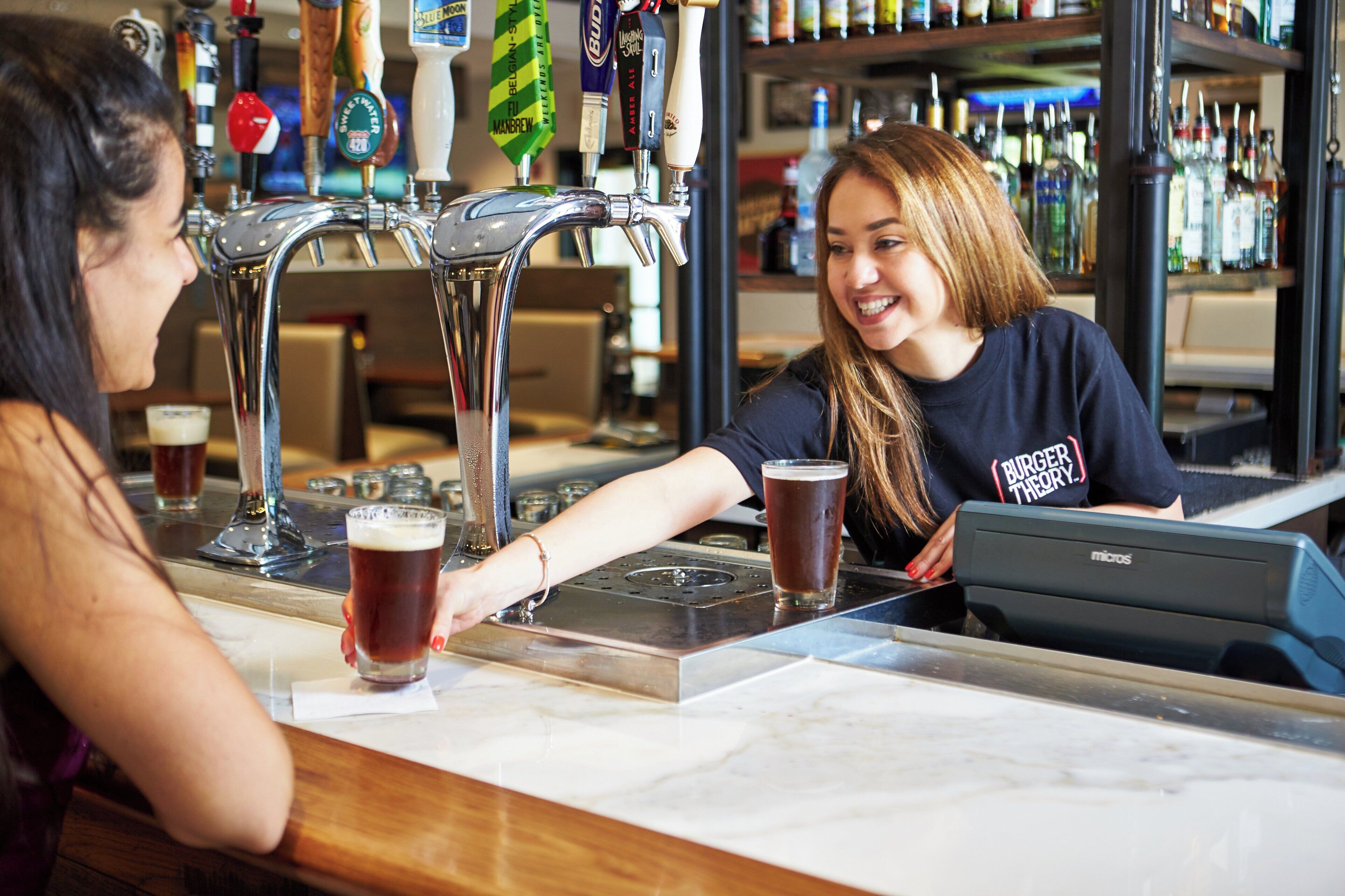 Un bar con una persona sirviendo una bebida en un vaso.
