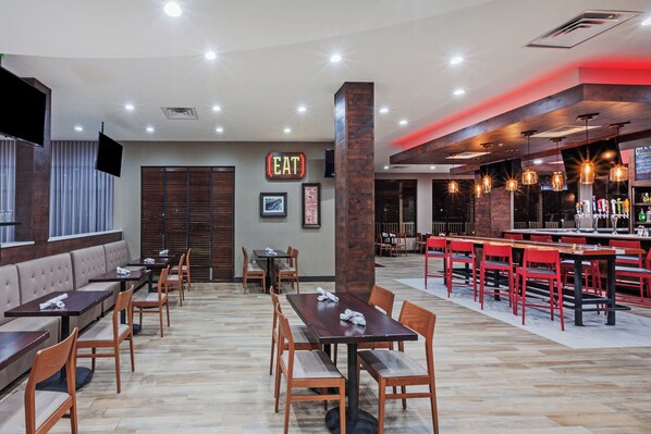A restaurant with booths and tables, a bar area, and a sign that reads 'EAT'.
