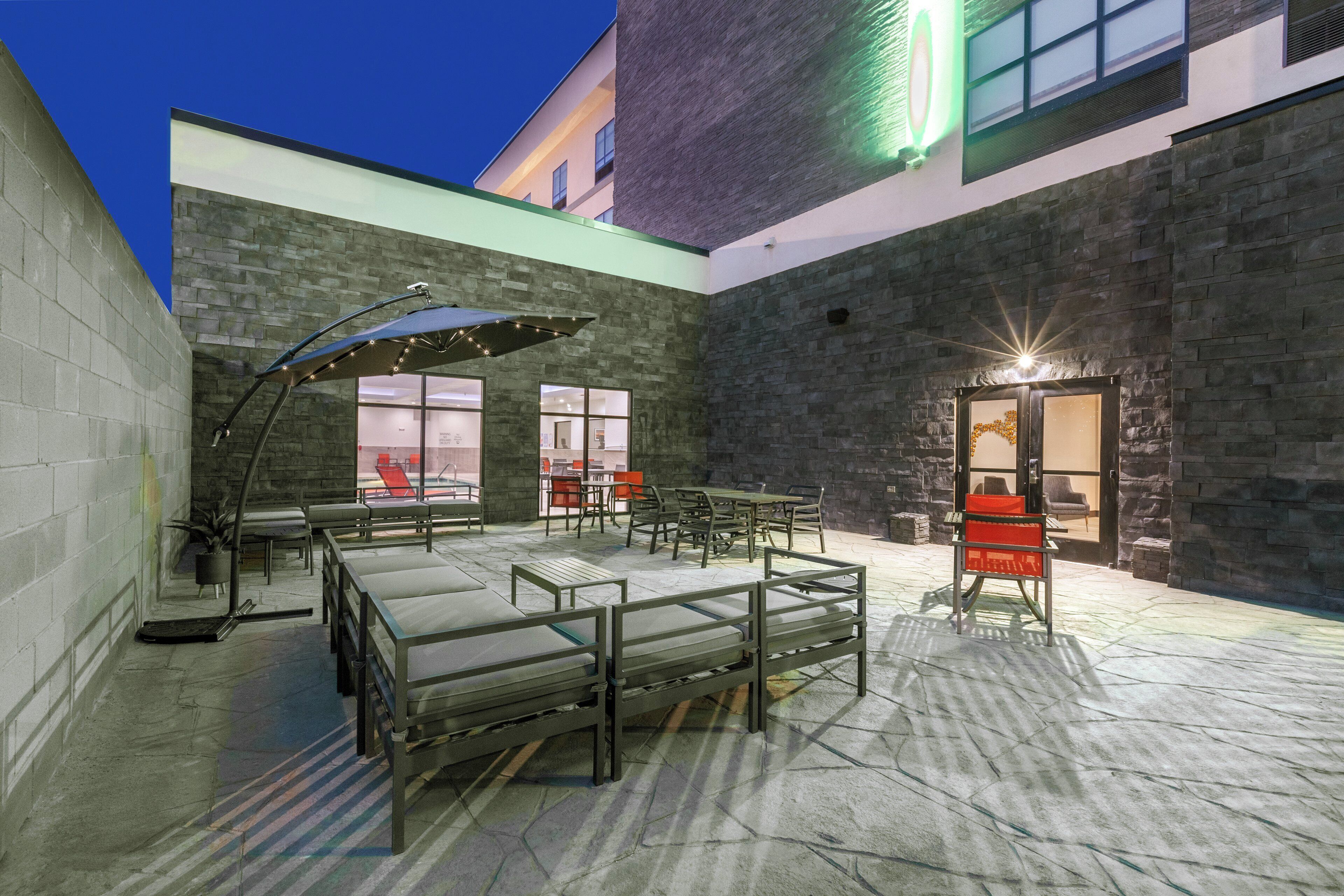 A courtyard with outdoor seating, a covered area, and a building entrance.