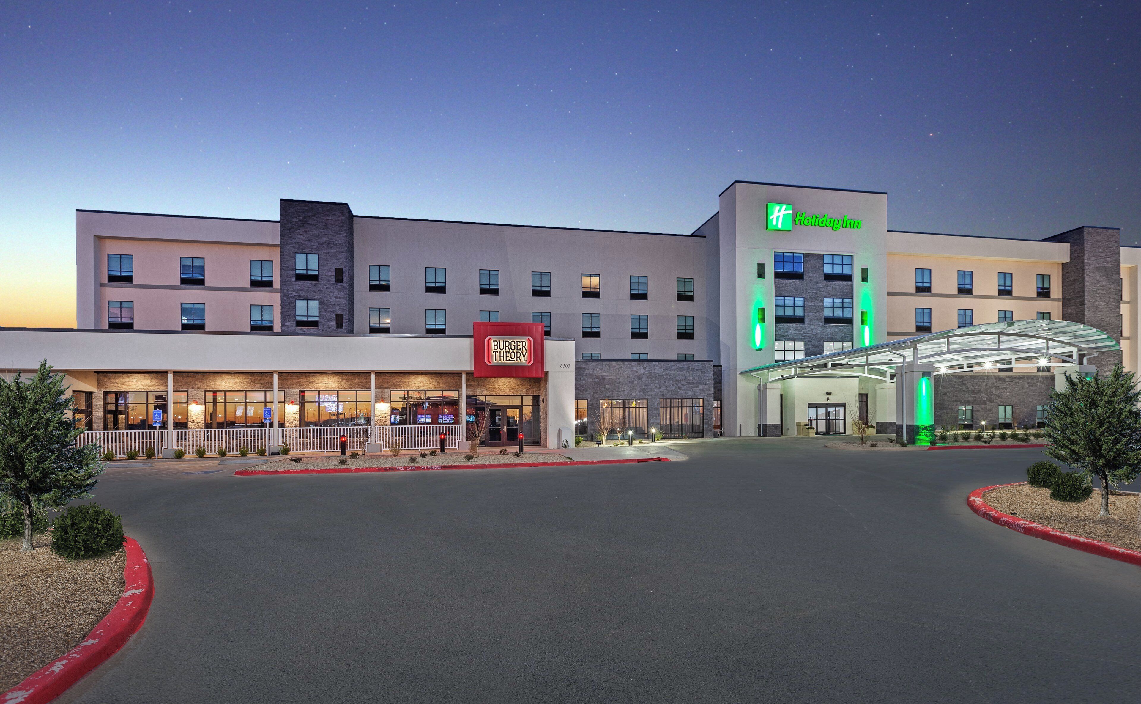 A Holiday Inn hotel with a Burger Theory restaurant, a covered entrance, and a clear sky.