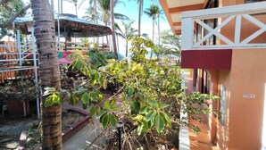 A tropical resort with palm trees, a covered seating area, and a building with a white and red facade. - Punta Riviera Resort Bolinao (Bolinao)