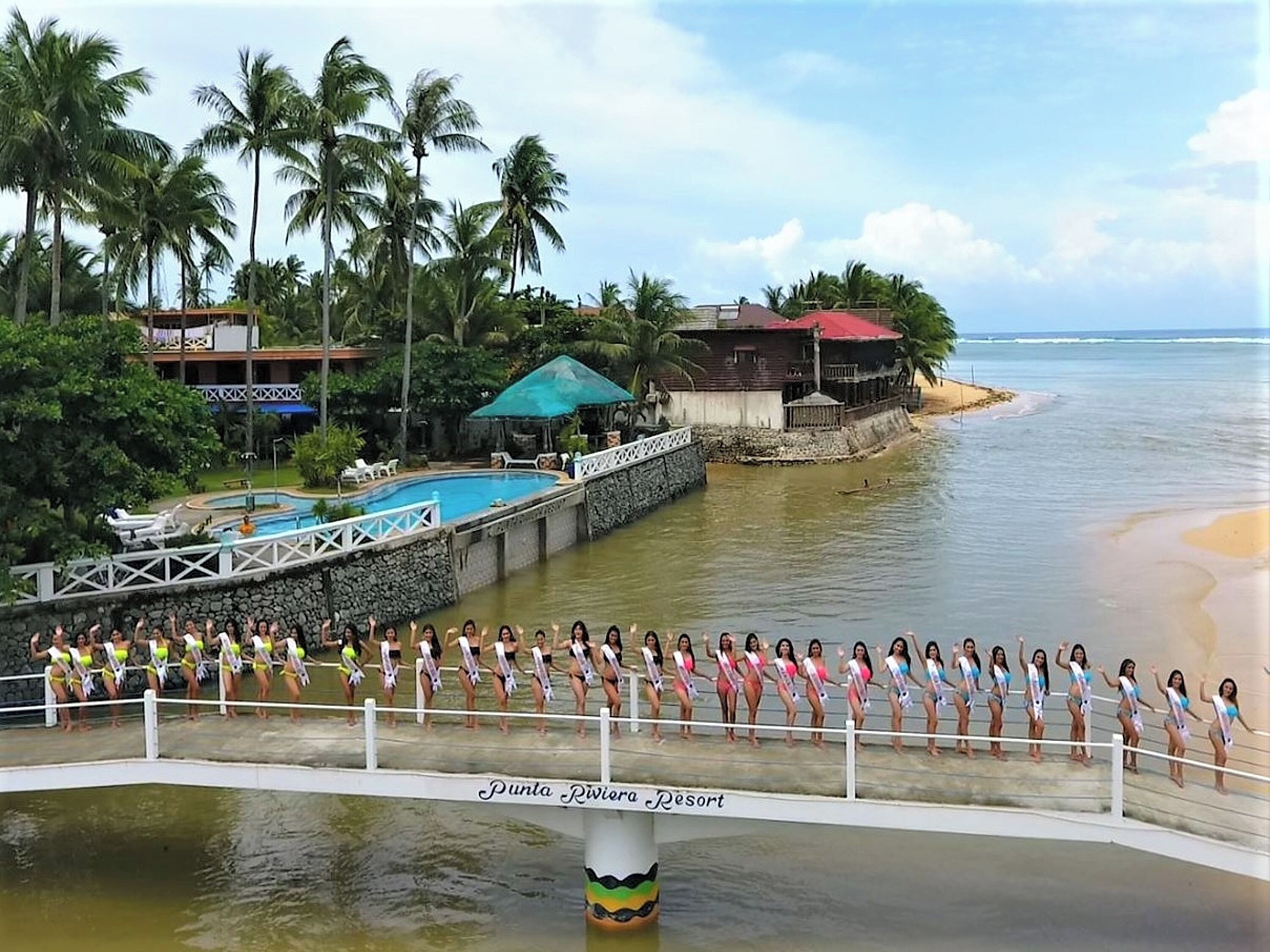 A resort with a swimming pool, palm trees, and a beach.