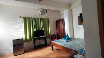 Une chambre avec un lit, une télévision, une armoire et un ventilateur de plafond.