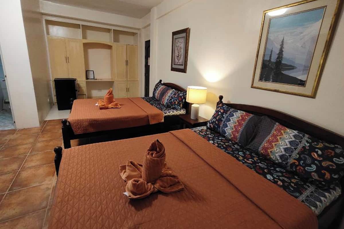 A hotel room with two beds, a sofa, a desk, and a framed picture on the wall.