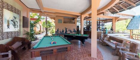 Ein Poolbereich mit Billardtisch, Sitzgelegenheiten und einer Bar.