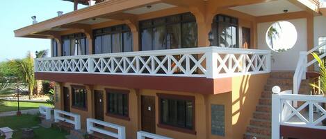 A two-story building with a balcony, a staircase, and a well-maintained lawn.