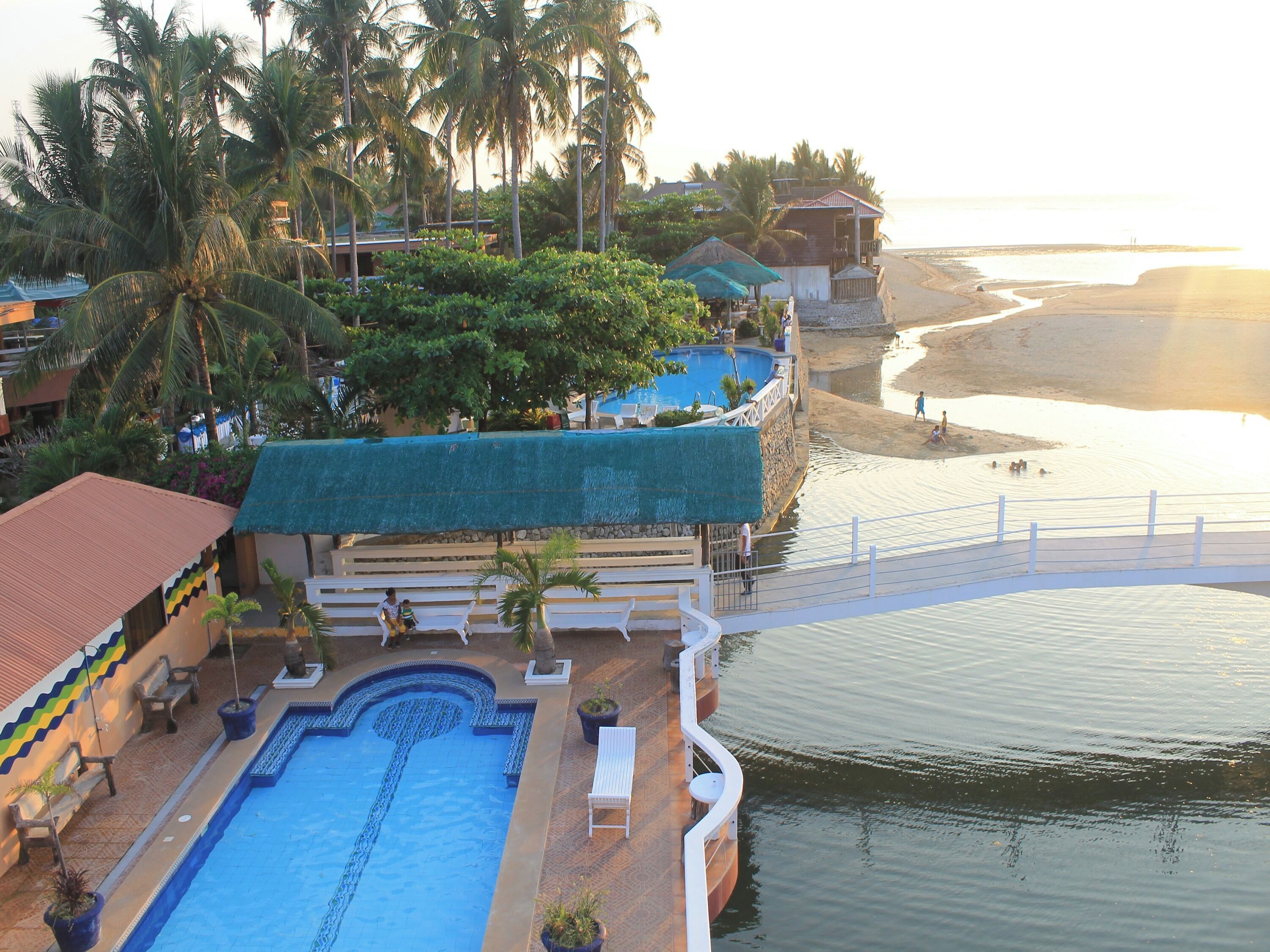 Un resort con piscina, accesso alla spiaggia e palme.