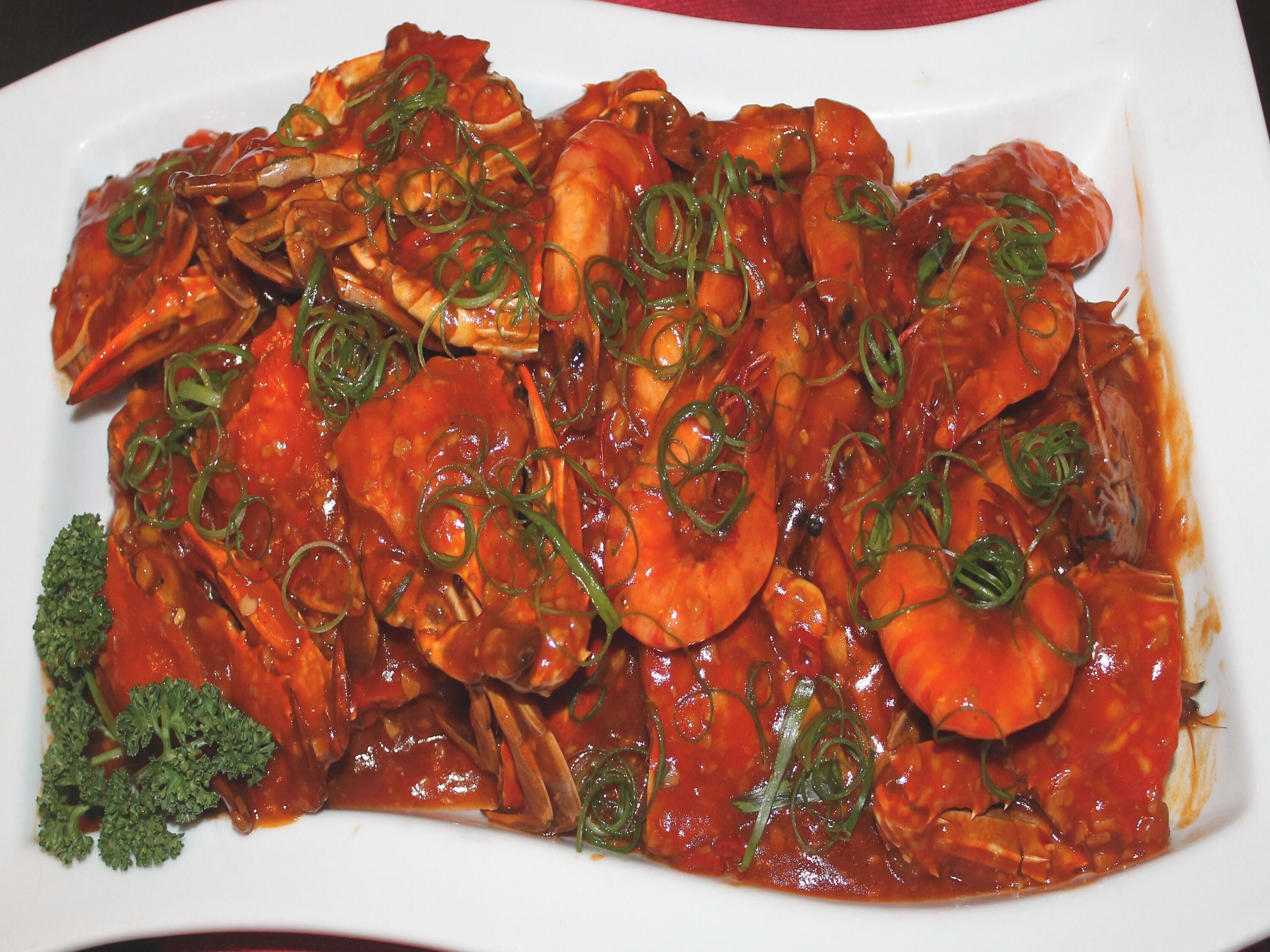 Un plato de camarones salteados con vegetales y una guarnición de cebollines.