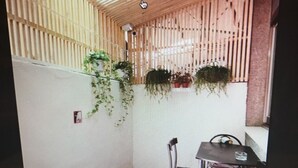 A small room with a sloped ceiling, wooden paneling, a tiled floor, a chair, a table, and potted plants. - Tainan Jie Guo Inn (Tainan)