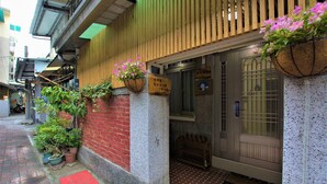 A traditional Japanese building with a red brick wall, a wooden slatted entrance, and potted plants. - Tainan Jie Guo Inn (Tainan)